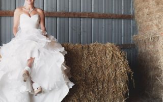 A woman in white wedding dress sitting on brown hay