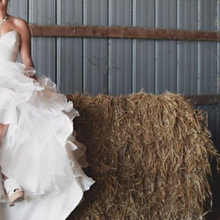 A woman in white wedding dress sitting on brown hay