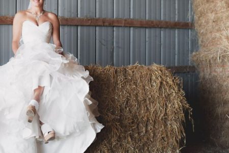 A woman in white wedding dress sitting on brown hay